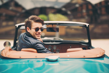 Fashion man sitting in luxury retro cabriolet car outdoorsの写真素材