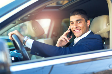 Businessman talk in car. Confident businessman talking on the mobile phone and looking away while...