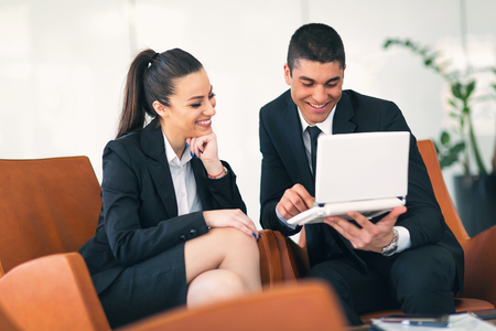 Colleague Team, businessman and businesswoman sitting in armchairs using gadgetsの写真素材