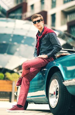 Fashion man standing near retro cabriolet car outdoorsの写真素材