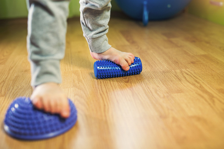 Flat feet correction exercise. Little boy using spiked rubber rollerの写真素材