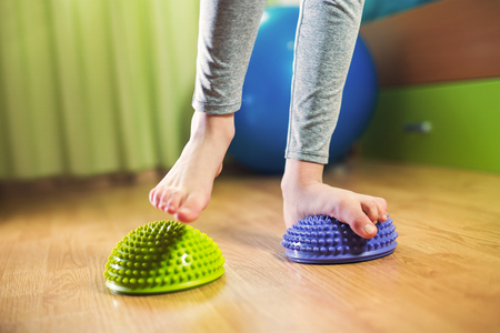 Flat feet correction exercise. Girl walking over spiked half balance massage ballsの写真素材
