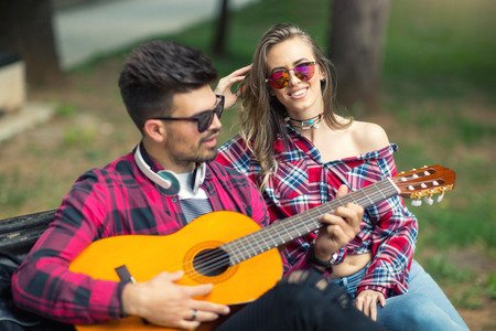 Happy Couple at the Park Playing Guitar and Singing Songs.の写真素材