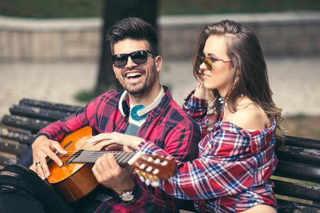 Happy Couple at the Park Playing Guitar and Singing Songs.の写真素材