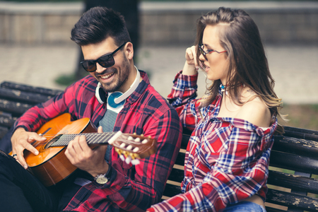 Happy Couple at the Park Playing Guitar and Singing Songs.の写真素材