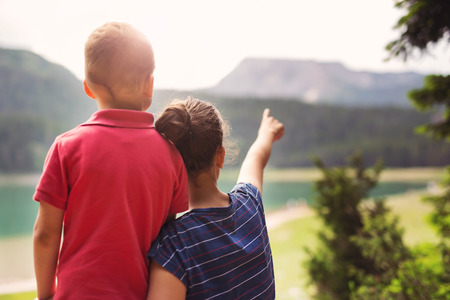 Young boy and girl looking at the lakeの写真素材