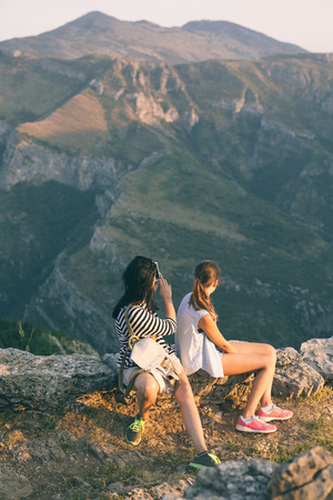 Mother and daugther photographing on mountain peak, whilst restingの写真素材