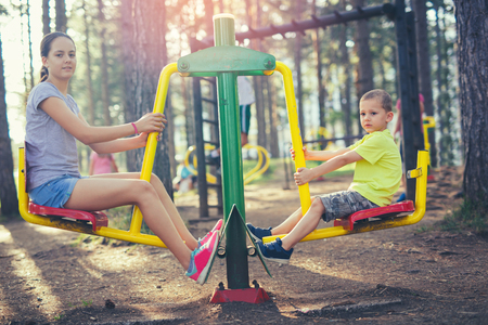 Brother and sister are exercise outdoors in a park with exercise machinesの写真素材