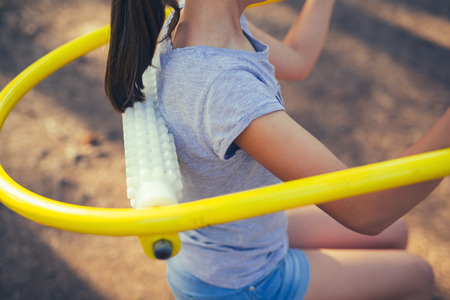 Young smiling teenage girl does exercises at massager simulator in parkの写真素材