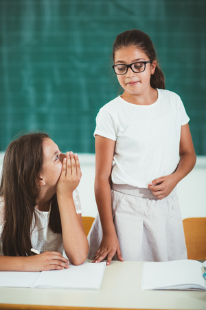 One girl responds while others whispering in classroomの写真素材