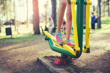 Teenage girl doing exercises at simulator in park, close upの写真素材