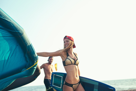Pretty smiling Caucasian woman kitesurfer walking on the beach with her kiteの写真素材