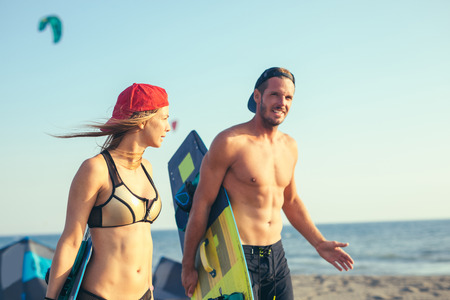 Pretty smiling Caucasian woman kitesurfer enjoying summertime on sandy beach with her boyfriend.の写真素材