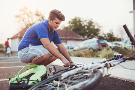 Teenager boy repair tire on bicycle summer outdoor photoの写真素材