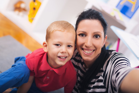 Mother with child photoshooting on smartphone selfie in the home roomの写真素材