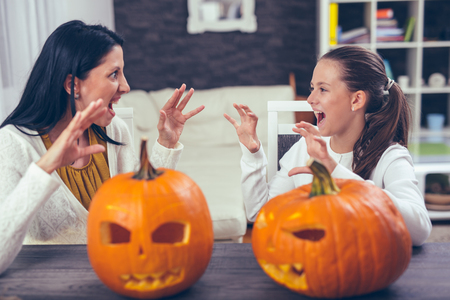 Mother with daughter creating big orange pumpkin for Halloween and having funの写真素材