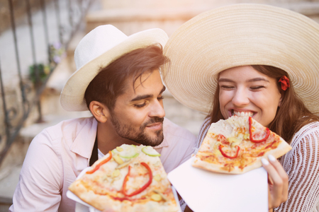 Happy couple of tourist eating pizza on streetの写真素材