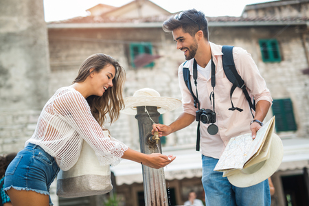 Young couple of tourist near a drinking fountain with waterの写真素材
