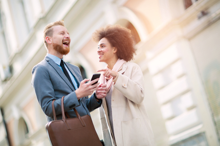 Happy business couple using smart phone outdoorsの写真素材