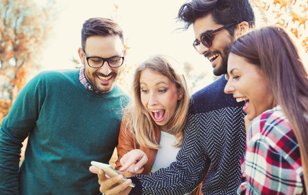 Group of young people in park with smart phoneの写真素材
