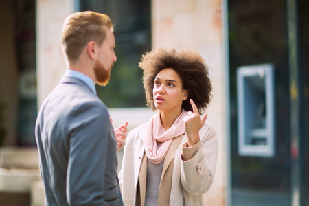 Two business people in an informal conversation in front of a business buildingの写真素材