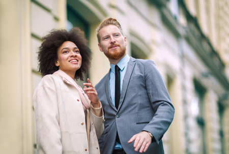 Two business people in an informal conversation in front of a business buildingの写真素材