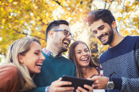 Group of young people in park with smart phoneの写真素材