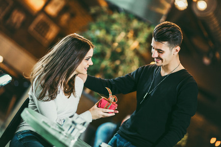 Young man gives a gift to a young girl in the cafeの写真素材