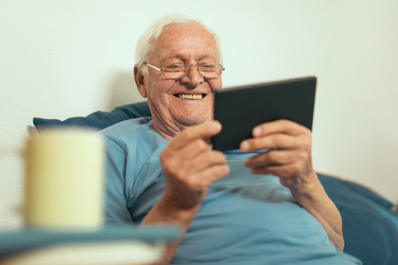 Senior man using digital tablet. Surprised mature male using portable computer at homeの写真素材