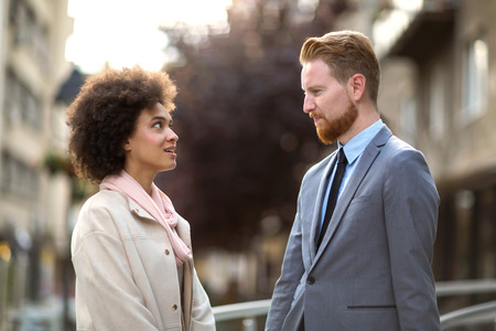 Two business people in an informal conversation in front of a business buildingの写真素材