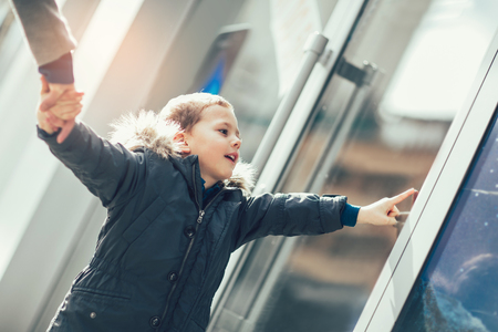Sweet little boy, looking through a window in shopの写真素材