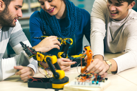 Young students of robotics preparing robot for testing in workshop