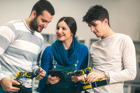 Young students of robotics preparing robot for testing in workshop