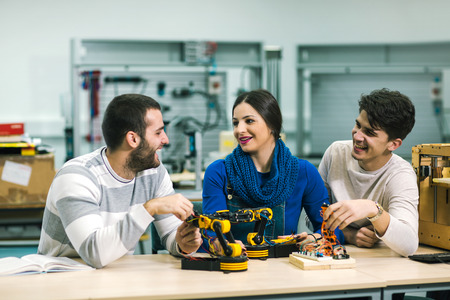 Young students of robotics preparing robot for testing in workshop