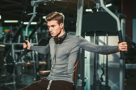 Young handsome man in sportswear exercising at gym