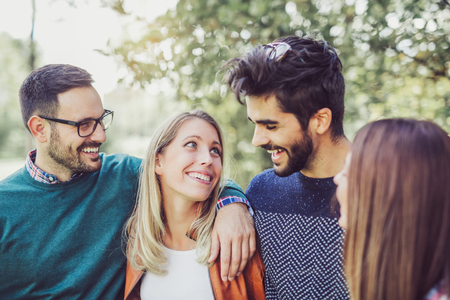Image of four happy smiling young friends walking outdoors in the park. Love, happiness and friendship conceptの写真素材