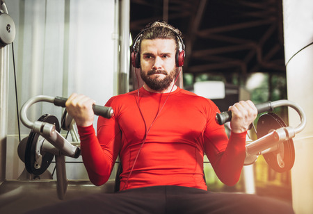 Young handsome man in sportswear exercising at gym