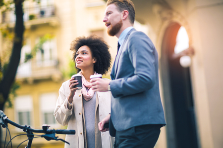 Two business people in an informal conversation in front of a business buildingの写真素材