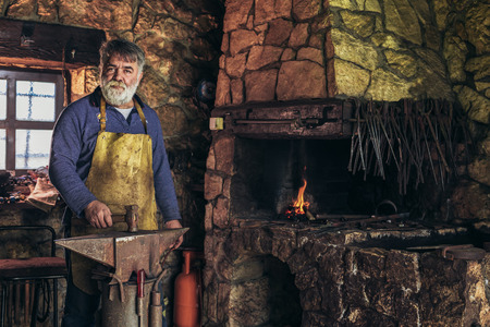 Senior blacksmith forge iron at work