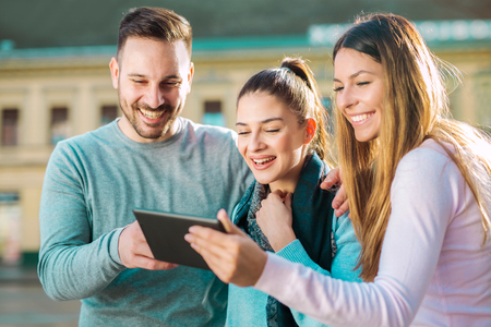Group of smiling friends with digital tablet outdoorの写真素材