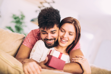 Man giving a surprise gift to woman at homeの写真素材