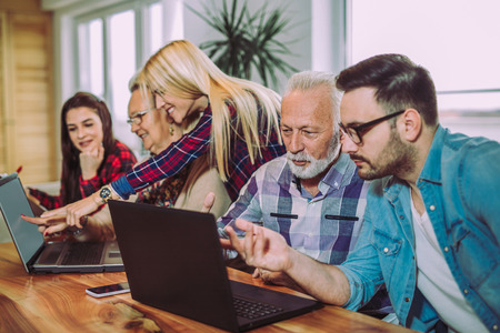 Young volunteers help senior people on the computerの写真素材