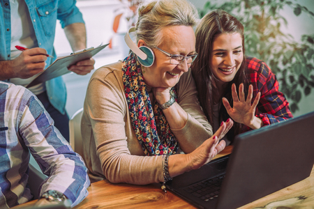 Young volunteers help senior people on the computerの写真素材