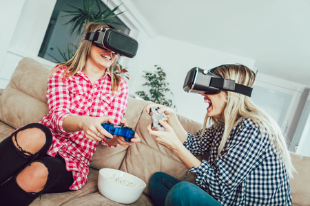 Girls hold modern devices, VR glasses and inspect, study possibilities of gadget and communicate with each otherの写真素材