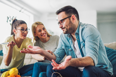 Two women and a man in a living room holding a credit cardの写真素材