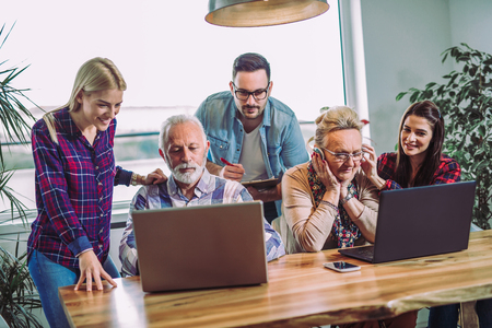 Young volunteers help senior people on the computer