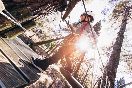 Happy boys playing at adventure park on sunny day. Boy enjoys climbing in the ropes course adventure.の写真素材