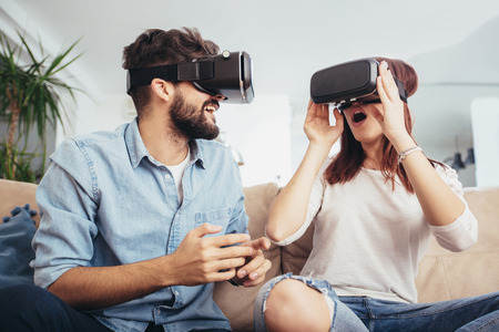 Young man and woman in casual clothes wear the virtual reality glasses are watching and showing...