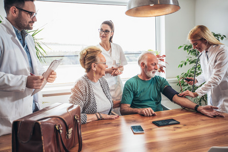 Image of young medic taking blood pressure during home visitの写真素材