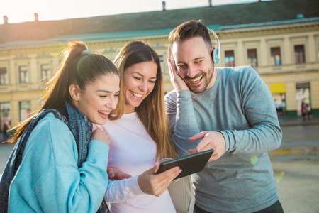 Group of smiling friends with digital tablet outdoorの写真素材
